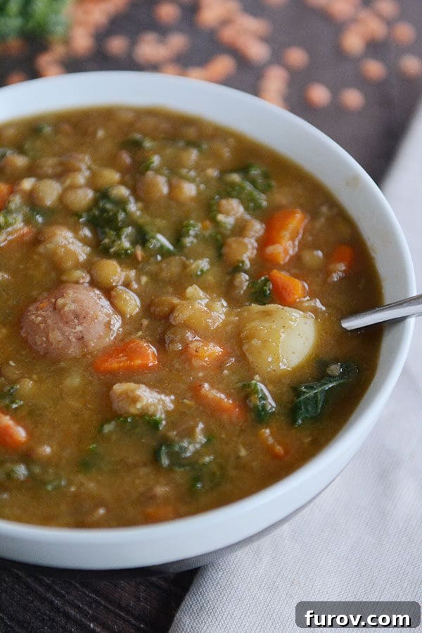 A bowl of steaming, hearty lentil and potato soup, garnished with fresh herbs, showcasing its rich texture and inviting warmth.