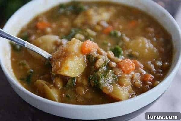 A beautifully presented bowl of smoky lentil soup with visible chunks of potato, carrots, and a hint of green spinach, ready for a cozy meal.