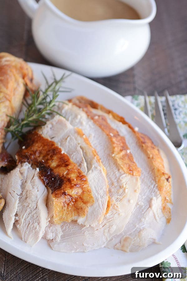 Simple Herb Roasted Turkey with Foolproof Gravy 2 Thick turkey slices cut up on a white oval platter, garnished with fresh herbs.