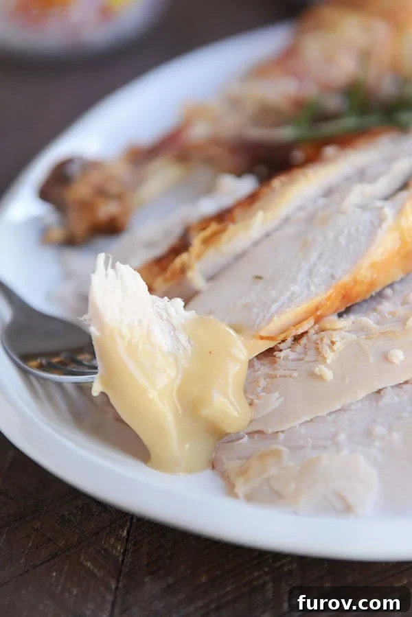Simple Herb Roasted Turkey with Foolproof Gravy 4 A fork taking a bite of perfectly cooked turkey from a platter of sliced turkey.