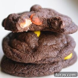 Close-up of a stack of Triple Chocolate Fudge Peanut Butter Cookies, featuring creamy peanut butter chips and chocolate chips visible on their fudgy surface.