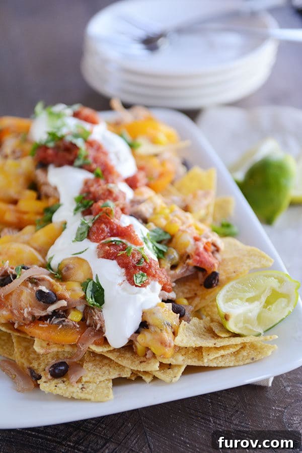 A vibrant platter of cheesy fajita nachos generously topped with fresh salsa and a dollop of sour cream, ready to be devoured.