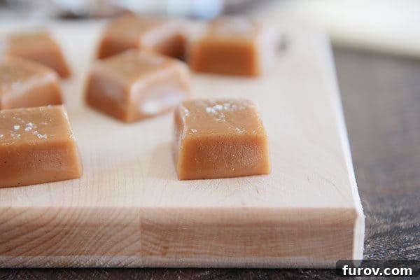Perfect Vanilla Bean Caramels A Step-by-Step Guide 4 Squares of perfectly cut vanilla bean caramel arranged on a rustic wooden cutting board.