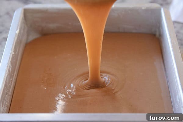 Perfect Vanilla Bean Caramels A Step-by-Step Guide 6 Liquid caramel being carefully poured into a metal tin, ready to set.