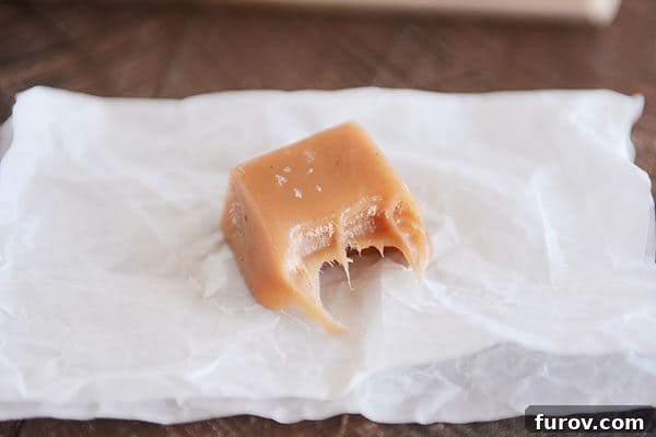 Perfect Vanilla Bean Caramels A Step-by-Step Guide 7 A square of salted vanilla bean caramel with a bite taken out, revealing its soft, chewy interior.