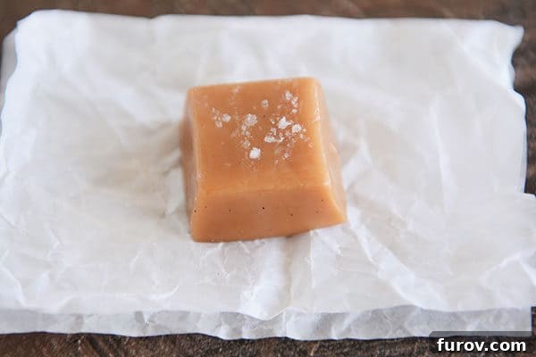Perfect Vanilla Bean Caramels A Step-by-Step Guide 8 A perfectly formed square of salted vanilla bean caramel on a piece of parchment paper.