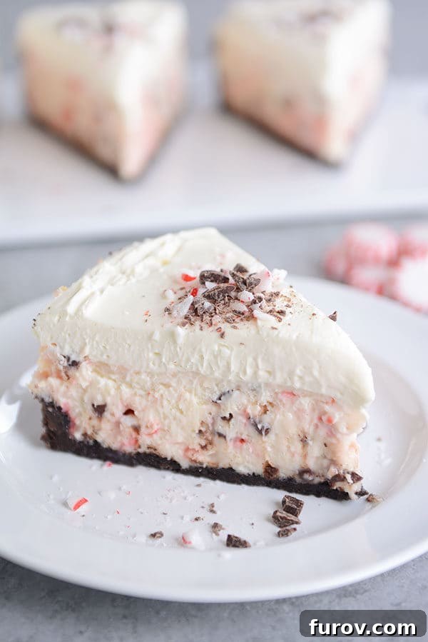 A slice of layered white chocolate peppermint cheesecake on a white plate, showcasing its beautiful layers.