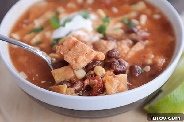 Easy Chicken Tortilla Soup Instant Pot Stovetop Slow Cooker 10 A spoon taking a bite out of a bowl of red chicken tortilla soup.