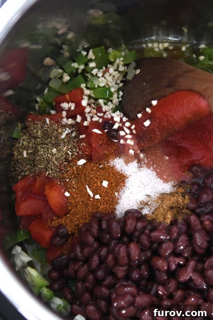 Easy Chicken Tortilla Soup Instant Pot Stovetop Slow Cooker 3 Top down view of an InstantPot filled with black beans, spices, diced green peppers, and crushed tomatoes.