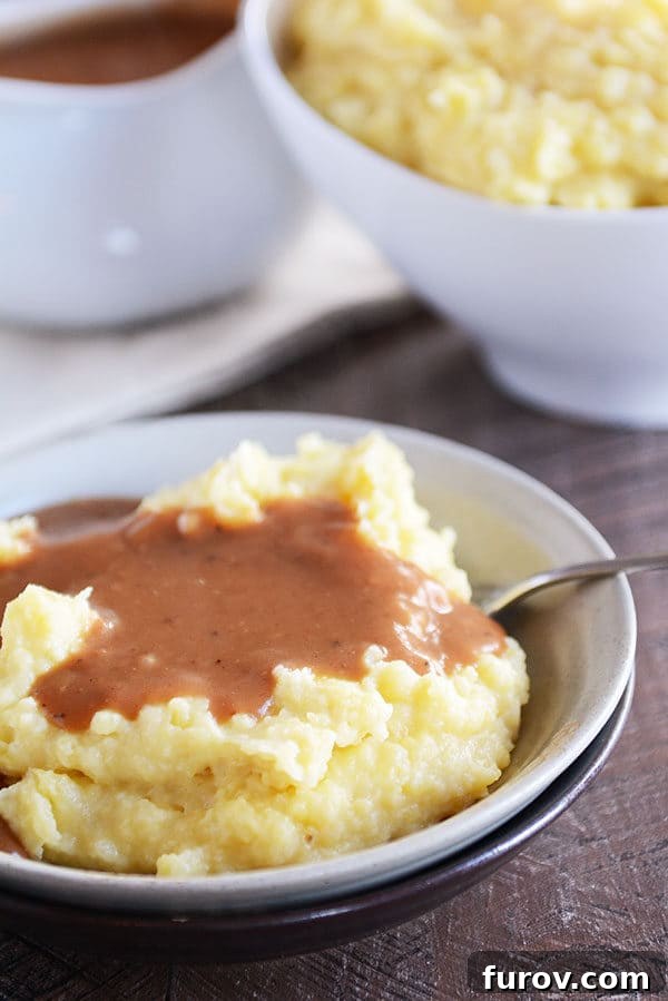 A bowl full of mashed potatoes topped with brown gravy.