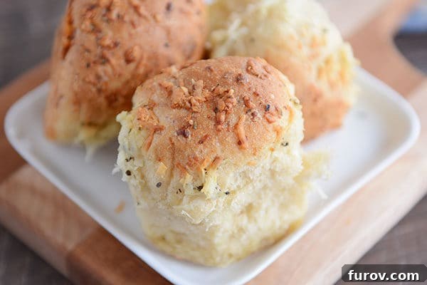 Golden Asiago Pull-Apart Loaf 6 Three asiago cheese topped rolls on a small square plate.
