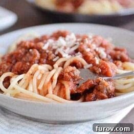 A vibrant, rich homemade spaghetti sauce, simmering gently, with a sprig of basil for garnish, inviting a delicious meal.