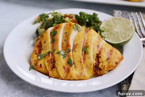 A vibrant white plate showcasing perfectly sliced grilled chicken alongside a fresh green salad and a bright lime wedge.