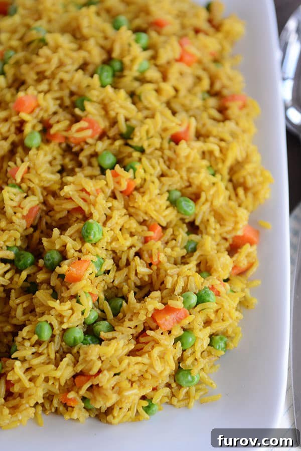 A beautiful white platter overflowing with fragrant Instant Pot Indian vegetable rice, perfectly fluffy and infused with a golden hue, dotted with vibrant peas and tender carrot pieces, ready for a family meal.