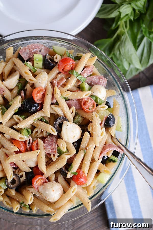 Top view of a pasta salad with olives, tomatoes, mozzarella, and onions, showcasing its vibrant colors.