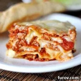 Classic Italian Lasagna slice with creamy white sauce and ground turkey, visually rich and inviting.