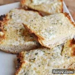 Close-up of baked cheesy garlic bread with perfectly melted cheese and a hint of fresh parsley garnish.