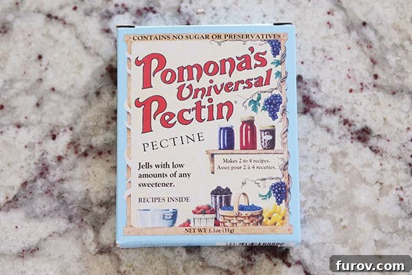 A simple white box of Pomona's Universal Pectin rests on a speckled granite countertop, ready to be used for homemade jam.