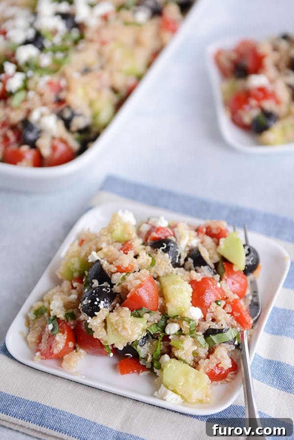 Top view of a square white plate with a large helping of Mediterranean quinoa salad.