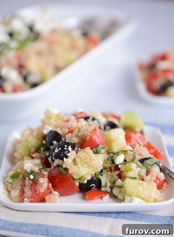 A square white plate of Mediterranean quinoa and vegetable salad. 