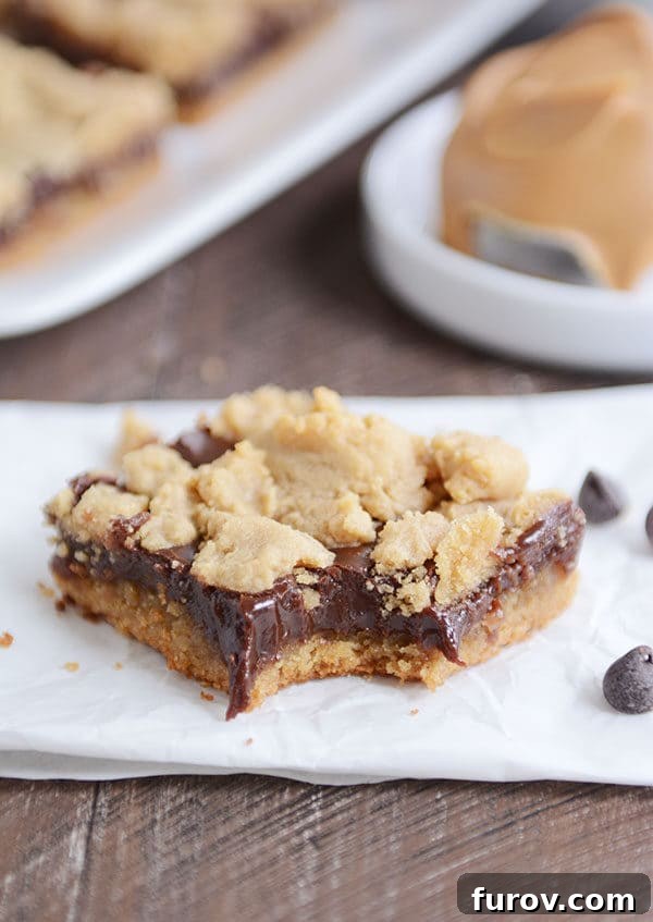 A perfectly portioned peanut butter fudge bar with a bite taken out, resting on parchment paper.