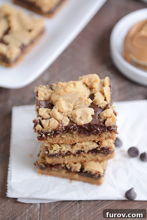 Three decadent peanut butter fudge bars stacked artistically, showcasing their layers.