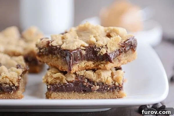A white serving tray filled with neatly cut peanut butter fudge bars, one with a bite taken out.