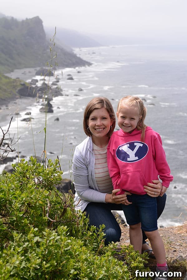 Effortless Wonders: Your Relaxed Guide to the Redwood Giants 23 A mother and daughter stand on a rocky beach, gazing out at the powerful ocean waves under a dramatic sky.