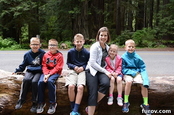 Effortless Wonders: Your Relaxed Guide to the Redwood Giants 7 A family rests on a fallen log in the lush Redwood forest, surrounded by nature's beauty.