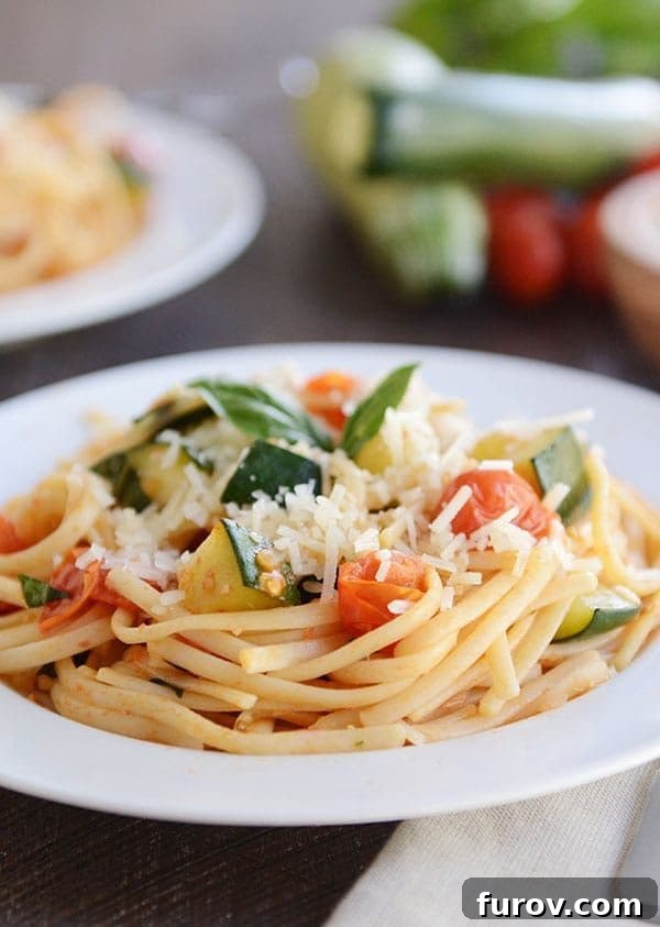 30-Minute Fresh Zucchini Tomato Linguine 4 A white plate of pasta with chopped zucchini and tomato on top.