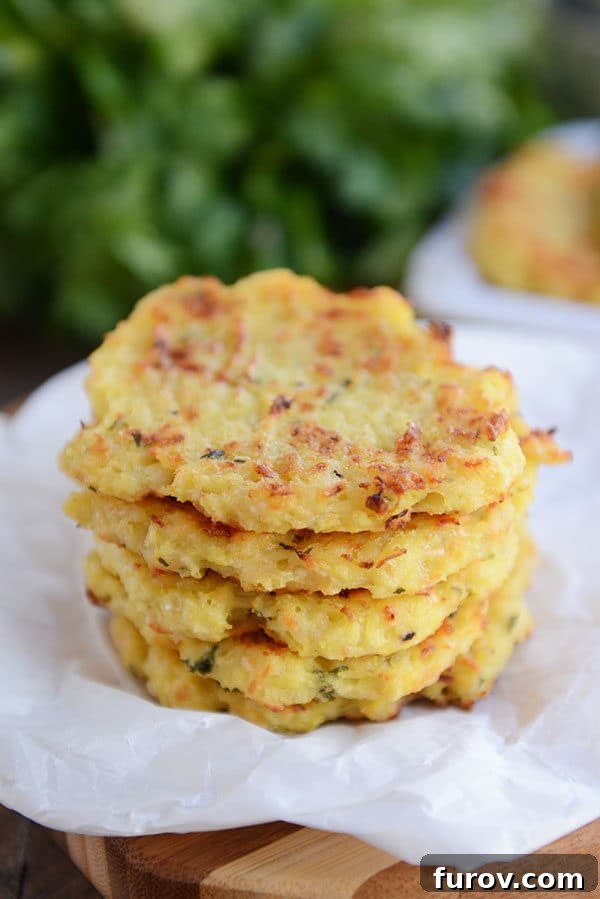 Crispy Baked Parmesan Spaghetti Squash Fritters 5 A neatly stacked arrangement of golden-brown baked spaghetti squash fritters on parchment paper, ready to be enjoyed.
