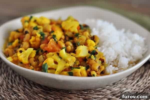 Curry and white rice in a white bowl, garnished with fresh cilantro.