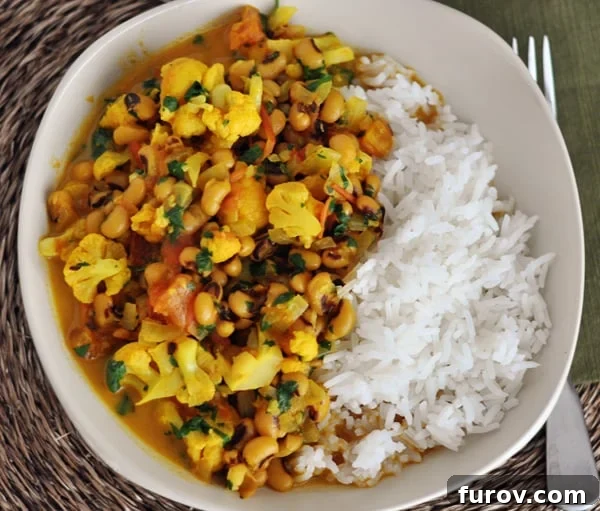 Top-down view of a white bowl filled with Black-Eyed Pea Curry and white rice, ready to be enjoyed.