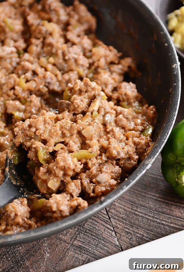 A skillet full of cooked beef sloppy joe mixture. 