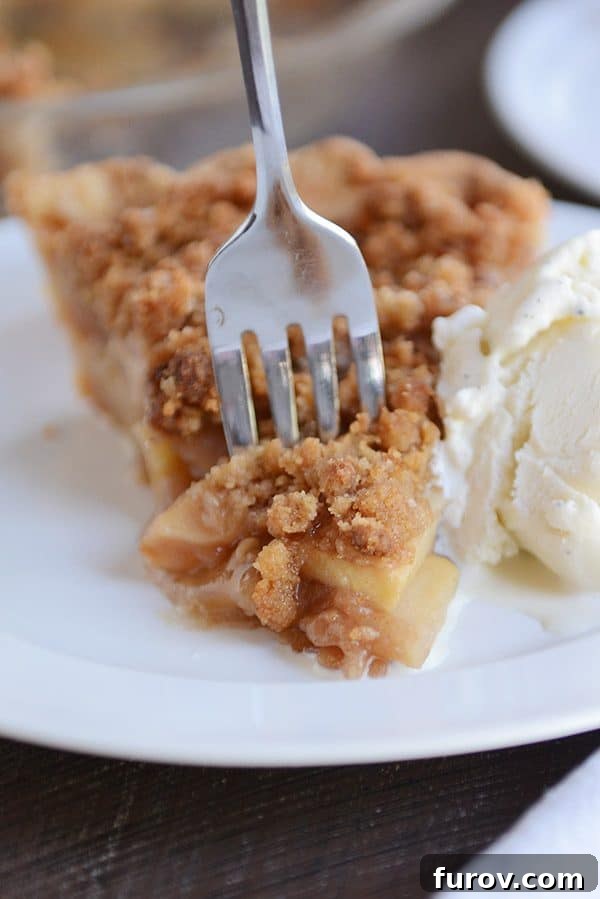 No-Fuss Apple Crumble Pie 4 A close-up shot of a fork digging into a slice of apple crumble pie, showcasing the tender apples and the irresistible crumbly topping.