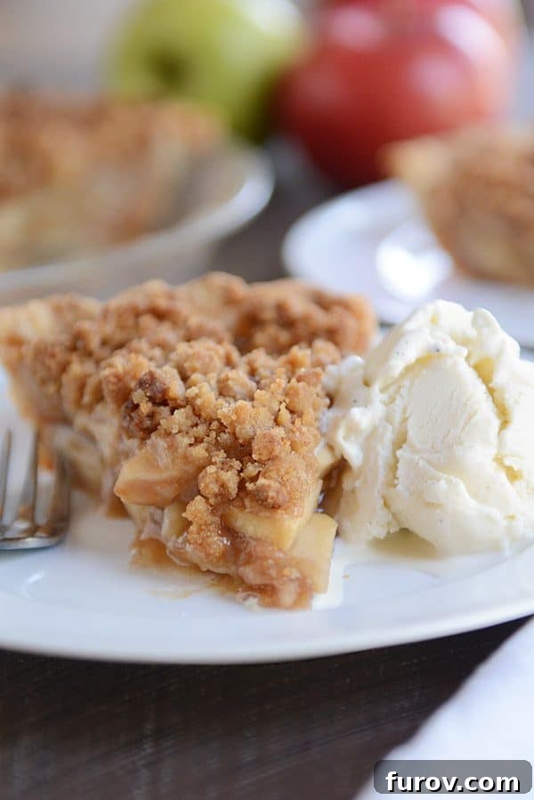 No-Fuss Apple Crumble Pie 6 A beautiful slice of apple crumble pie and a scoop of vanilla ice cream artfully arranged on a clean white plate.