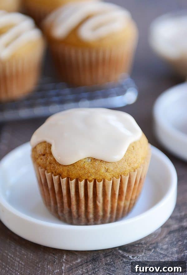 A single pumpkin muffin, generously covered in maple frosting, resting elegantly on a white ramekin.