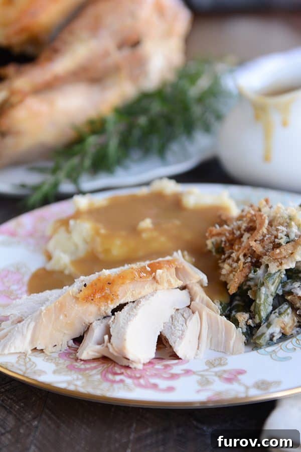 Juicy & Golden Thanksgiving Turkey in an Oven Roasting Bag 8 A white plate generously laden with carved turkey, a scoop of creamy green bean casserole, and fluffy mashed potatoes drizzled with gravy.