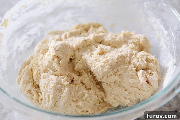 Roll dough resting in a glass bowl, ready for refrigeration.