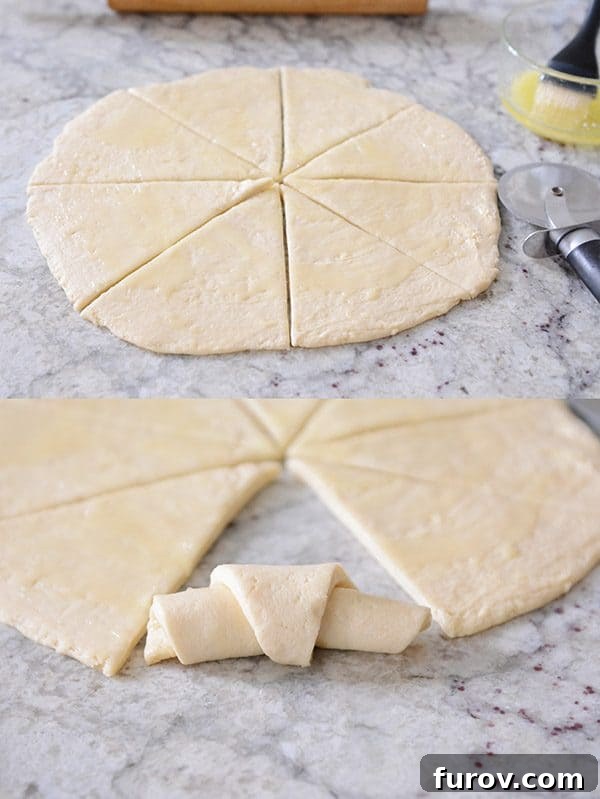 Flattened roll dough expertly cut into wedges, prepared for shaping into crescent rolls.