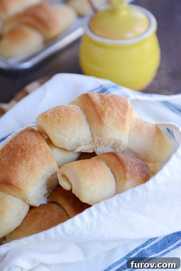 A napkin-lined basket overflowing with freshly baked, buttery crescent rolls.