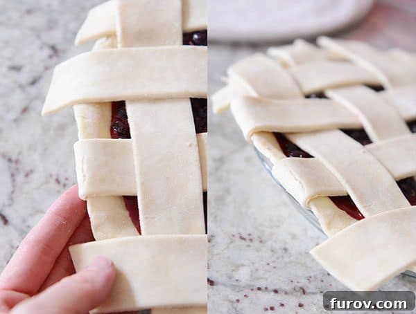 Side view of an uncooked lattice pie crust where the excess strips are being tucked neatly under the bottom crust.