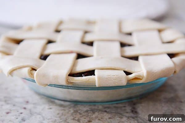 A perfectly assembled lattice pie crust in a glass dish, with all edges neatly tucked, ready for fluting.