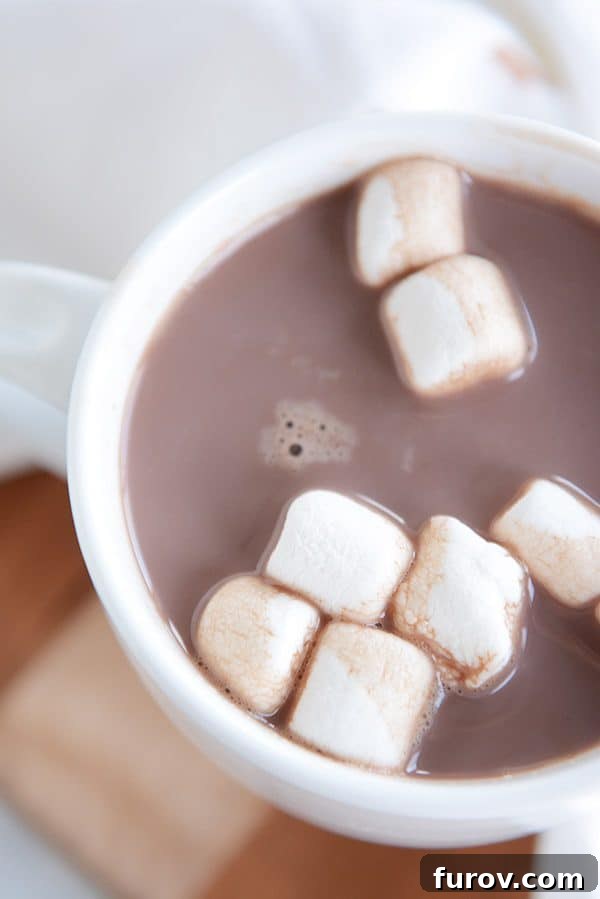 A top-view of a white mug of steaming hot chocolate and marshmallows floating on the top.