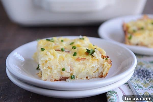 A piece of cheesy egg and hash brown casserole on a white plate.