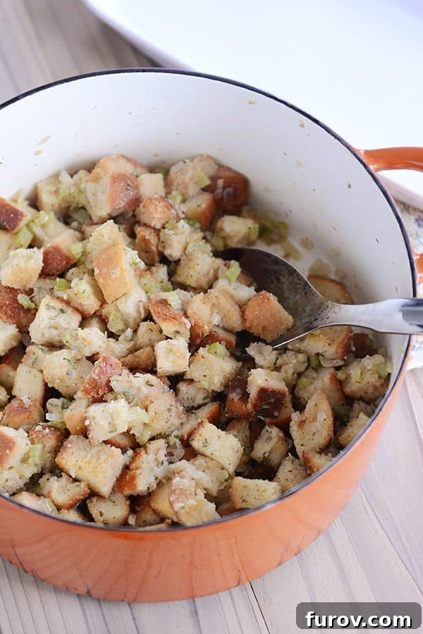 A large metal spoon taking a scoop of homemade stovetop stuffing out of an orange pot.
