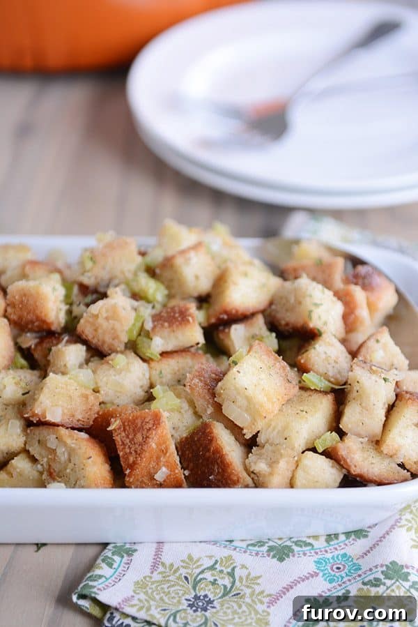 A white casserole dish of homemade stuffing, golden brown on top.