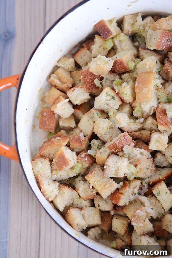Top view of an orange pot full of homemade stovetop stuffing, garnished with fresh herbs.