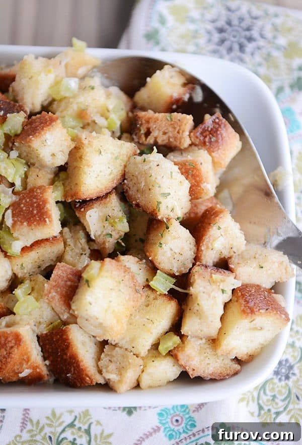 A white tray of golden-brown stuffing with a large metal spoon taking a scoop out.