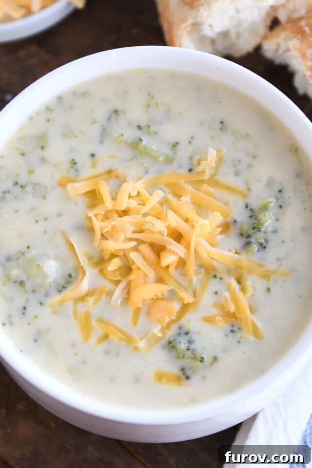Broccoli cheese soup with shredded cheddar in white bowl.